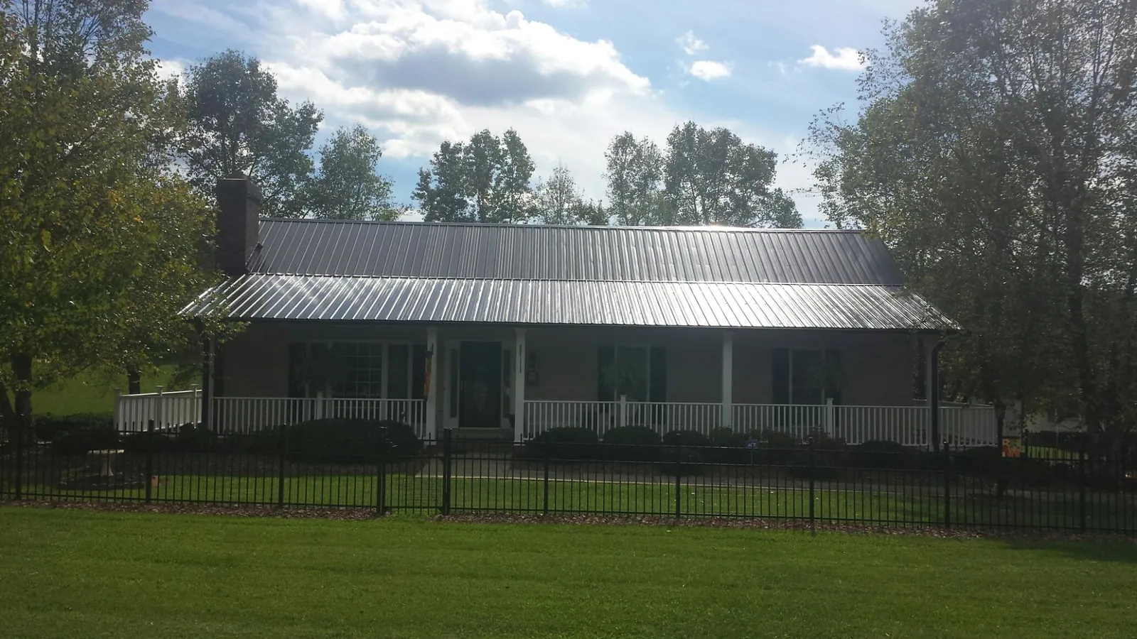 Gray metal roof on a brick ranch with a full width front porch — Gutter Guard Installation work by our crew in Middleton